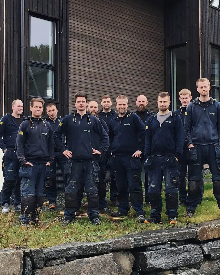 Tømrerne i Byggmesterfirma Finshus og Selvåg samlet foran et ferdig bygg.
